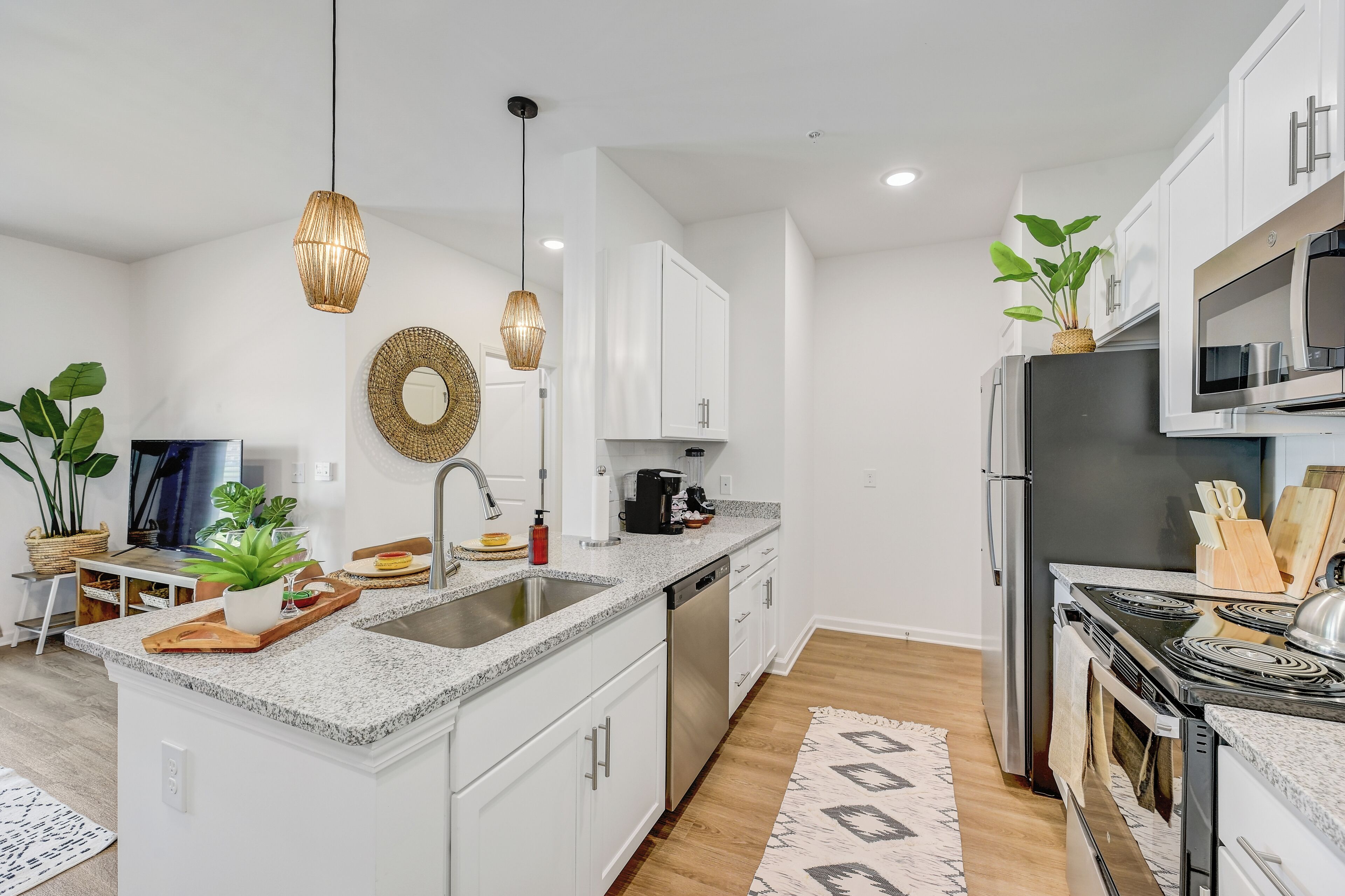 A modern kitchen with white cabinets, stainless steel appliances, a granite countertop, and a central island.