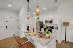 Una cocina moderna con armarios blancos, encimera de granito y una isla central con asientos.