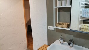 Ein Badezimmer mit einem weißen Waschbecken, einem Spiegel und einer Ablage für Pflegeprodukte.