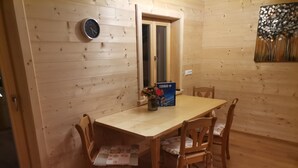 Ein Holzinterieur mit einem Esstisch, Stühlen, einer Uhr und einem gerahmten Kunstwerk.