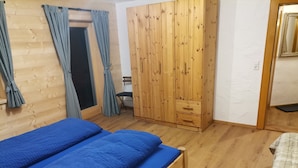 Ein Schlafzimmer mit einem Holzbett, einem Kleiderschrank und einem Sessel.