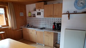 Eine kleine Küche mit Holzausstattung, einer Mikrowelle, einem Spülbecken und einem Esstisch.