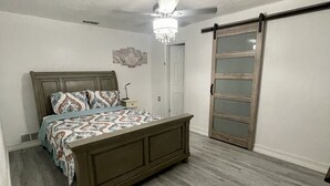 A bedroom with a bed, a chandelier, a wardrobe, and a sliding door.