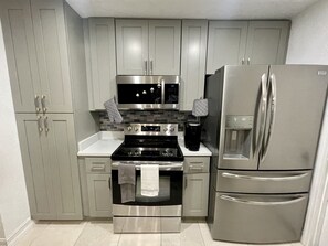Una cocina moderna con electrodomésticos de acero inoxidable, gabinetes grises y salpicadero de azulejos.