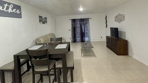 A living room with a dining table, chairs, a sofa, a TV, and a cabinet.