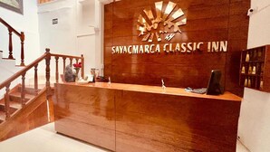 A reception desk with a wooden finish and a sign reading "SAYACMARCA CLASSIC INN". - SAYACMARCA CLASSIC INN (Machu Picchu)