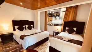 A hotel room with two beds, wooden flooring, and a view of the city through a large window. - SAYACMARCA CLASSIC INN (Machu Picchu)