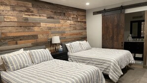 Une chambre d’hôtel avec deux lits, un mur décoratif en bois, une table de chevet avec une lampe et un placard à portes coulissantes.