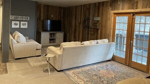 Un salon confortable avec un canapé, une petite table, un meuble sur lequel est posée une télévision et un tapis.