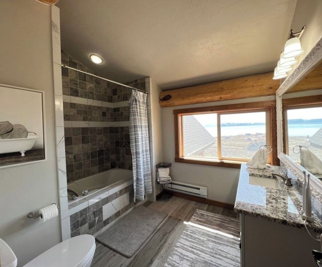 A bathroom with a bathtub, shower, and a window with a view.