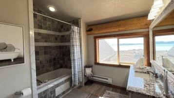A bathroom with a bathtub, shower, and a window with a view.