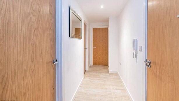 A hallway with wooden doors, a mirror, and a telephone. - Winkley House by Guestz (Preston)
