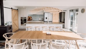 Een moderne keuken met een centraal eiland, witte kasten en een eethoek met een houten tafel en witte stoelen.