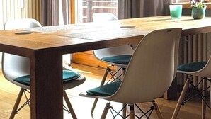 Een eetgedeelte met een houten tafel, stoelen en een hanglamp.