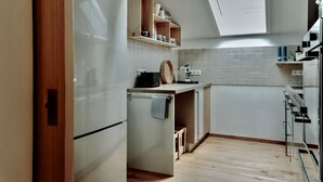 Een moderne keuken met witte kasten, een houten aanrecht en een dakraam.
