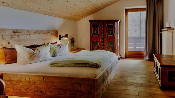 Een houten bed met hoofdeinde, nachtkastje en een kast met decoratieve panelen.