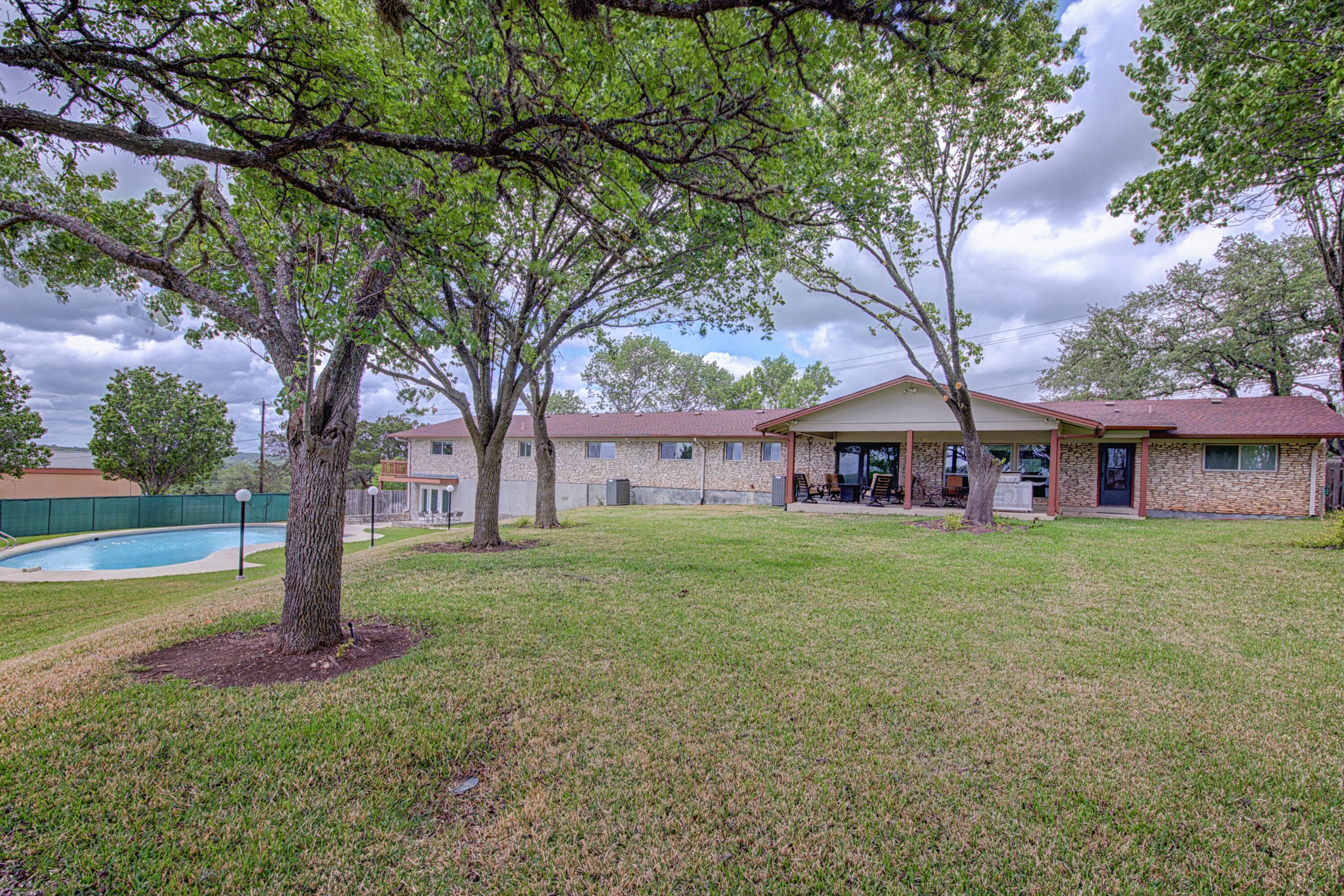 A residential property with a swimming pool, a covered patio, and a well-maintained lawn.