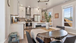 A modern kitchen with white cabinets, a central island, and a dining area with a round table and chairs.
