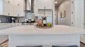 A modern kitchen with white cabinetry, a central island, and a stainless steel range hood.