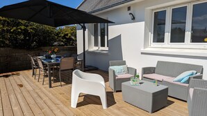 A wooden deck with outdoor furniture, a table set for dining, and a covered area with a table and chairs. - Spacious house 200m from Lilia's beaches & restaurants (Plouguerneau)