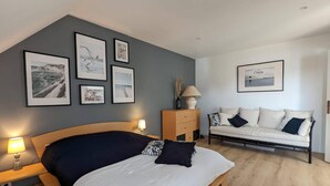 Une chambre à coucher comprenant un lit, des tables de chevet, une commode, un canapé et des tableaux encadrés accrochés au mur.