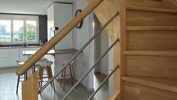 A modern kitchen with white cabinets, a stainless steel sink, and a dining area with stools. - Spacious house 200m from Lilia's beaches & restaurants (Plouguerneau)