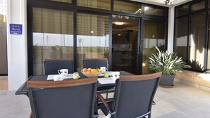 Un área de estar al aire libre con una mesa, sillas, un cuenco de fruta y una planta en maceta.