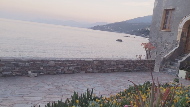 A stone-paved courtyard with a variety of flowers and a view of the sea. - Beautifully located studio in the heart of the village, renovated (Brando)