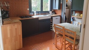 A compact kitchen with a sink, stove, and a small dining area with a table and chairs. - Large family home, between beaches and marshes. (Mesquer)