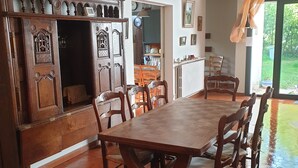 A dining area with a large wooden table and chairs, a wooden bench, and a view of the garden through a glass door. - Large family home, between beaches and marshes. (Mesquer)