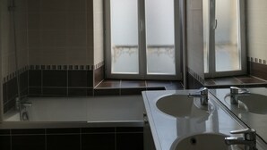 Un baño con dos lavamanos, una ducha y una puerta de vidrio esmerilado.