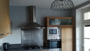 Una cocina moderna con electrodomésticos de acero inoxidable, armarios de madera y una estufa a gas.