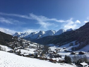 A snow-covered village with traditional wooden houses, a mountain backdrop, and a clear sky. - Top floor apartment, Aravis view - 6 guests (Le Grand-Bornand)