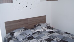 Une chambre à coucher avec une tête de lit en bois, un lit recouvert d’une literie à motifs et un mur décoré d’autocollants en forme d’étoiles.