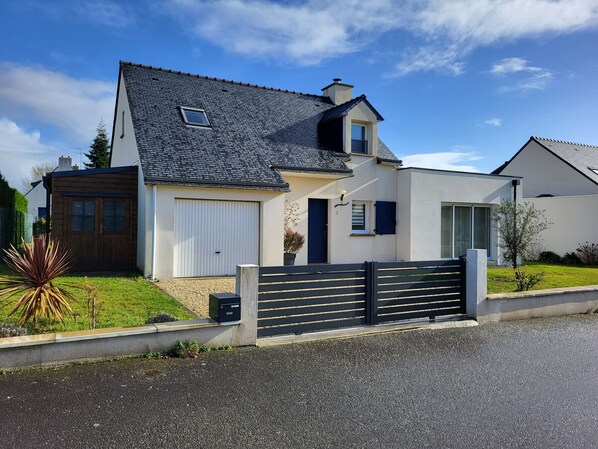 A modern two-story house with a garage, a small attached shed, and a black fence.