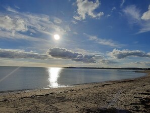 A beach with a calm sea, a clear sky, and the sun reflecting on the water. - Charming House for 6 near Beach, Shops, and Bike Rentals (Le Tour-du-Parc)