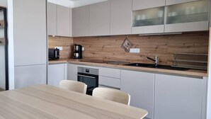Eine moderne Küche mit weißen Schränken, einer Holz Arbeitsplatte, einer Kaffeemaschine und einem Spülbecken.