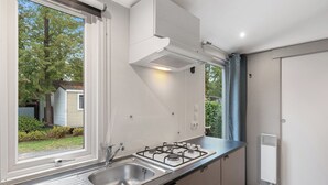 Une cuisine moderne dotée d’une grande fenêtre, d’un évier en acier inoxydable, d’une cuisinière à gaz et d’un four encastré.