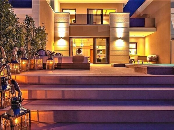 A modern building with a spacious outdoor seating area, steps leading to the entrance, and warm lighting.