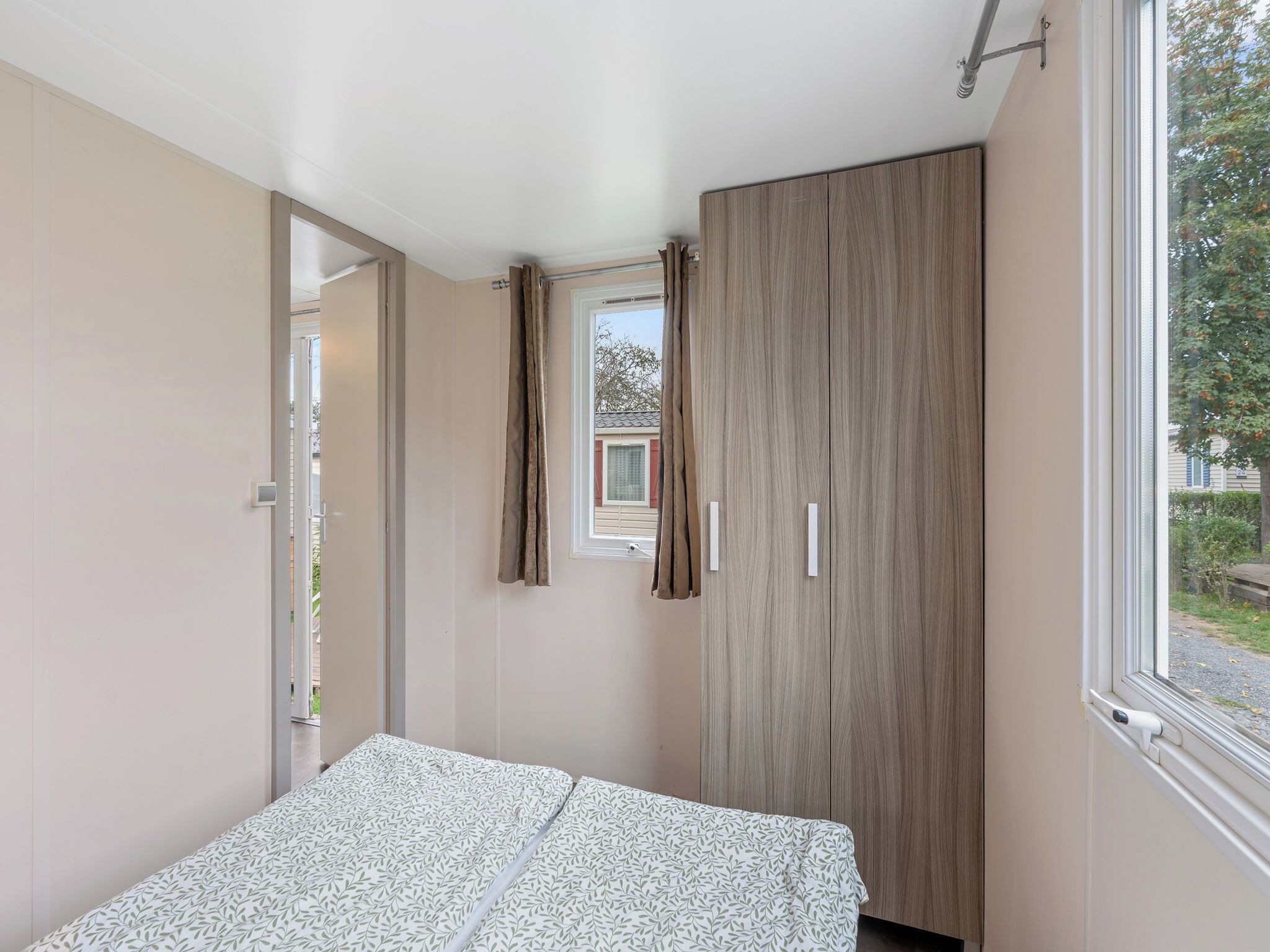 Een slaapkamer met een bed, een garderobe en een raam.