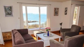 A living room with a sofa, armchairs, a coffee table, and a view of the sea. - Villa Hjartnes by Interhome (Baldersheim)