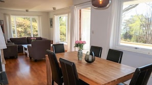 A dining area with a wooden table, black chairs, and a vase with flowers. - Villa Hjartnes by Interhome (Baldersheim)