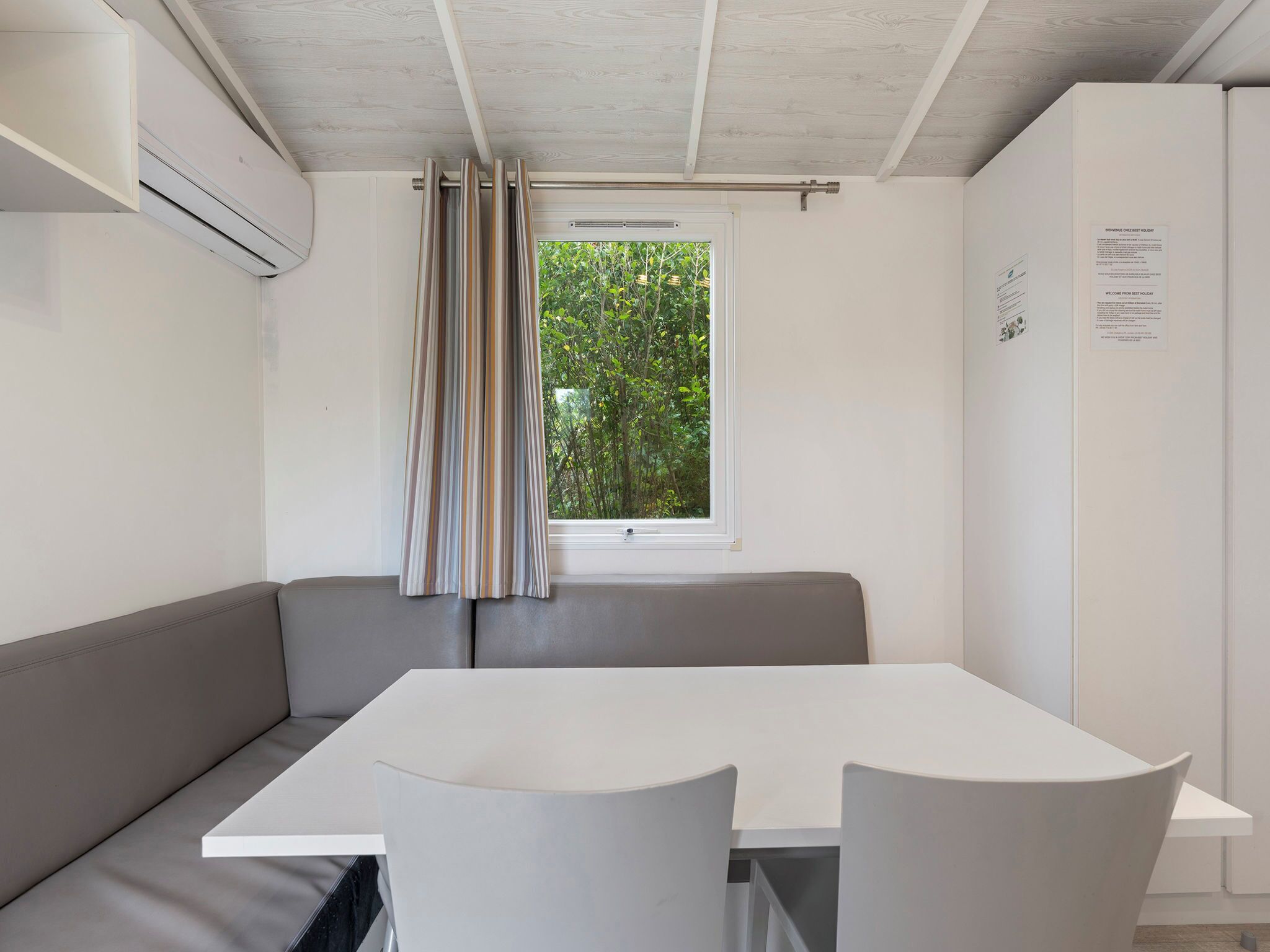 A modern room with a white table, grey sofa, and a window with striped curtains.