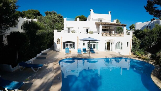 Eine moderne Villa mit Swimmingpool, Liegestühlen und einer überdachten Terrasse.
