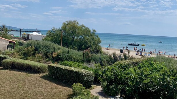 Ein Strand mit Menschen, Booten und einem Leuchtturm im Hintergrund.