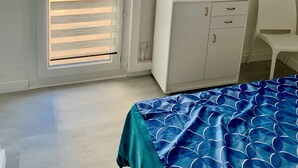 Ein Schlafzimmer mit Bett, Schrank, Schreibtisch und Stuhl.