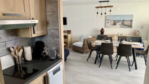 Eine moderne Küche mit Holzausstattung, einem Geschirrspüler und einem Essbereich mit Tisch und Stühlen.