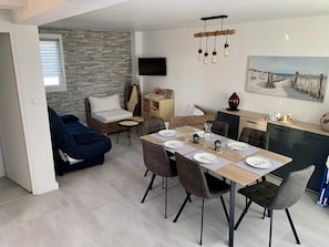 Ein modernes Wohnzimmer mit Sofa, Esstisch und Fernseher.