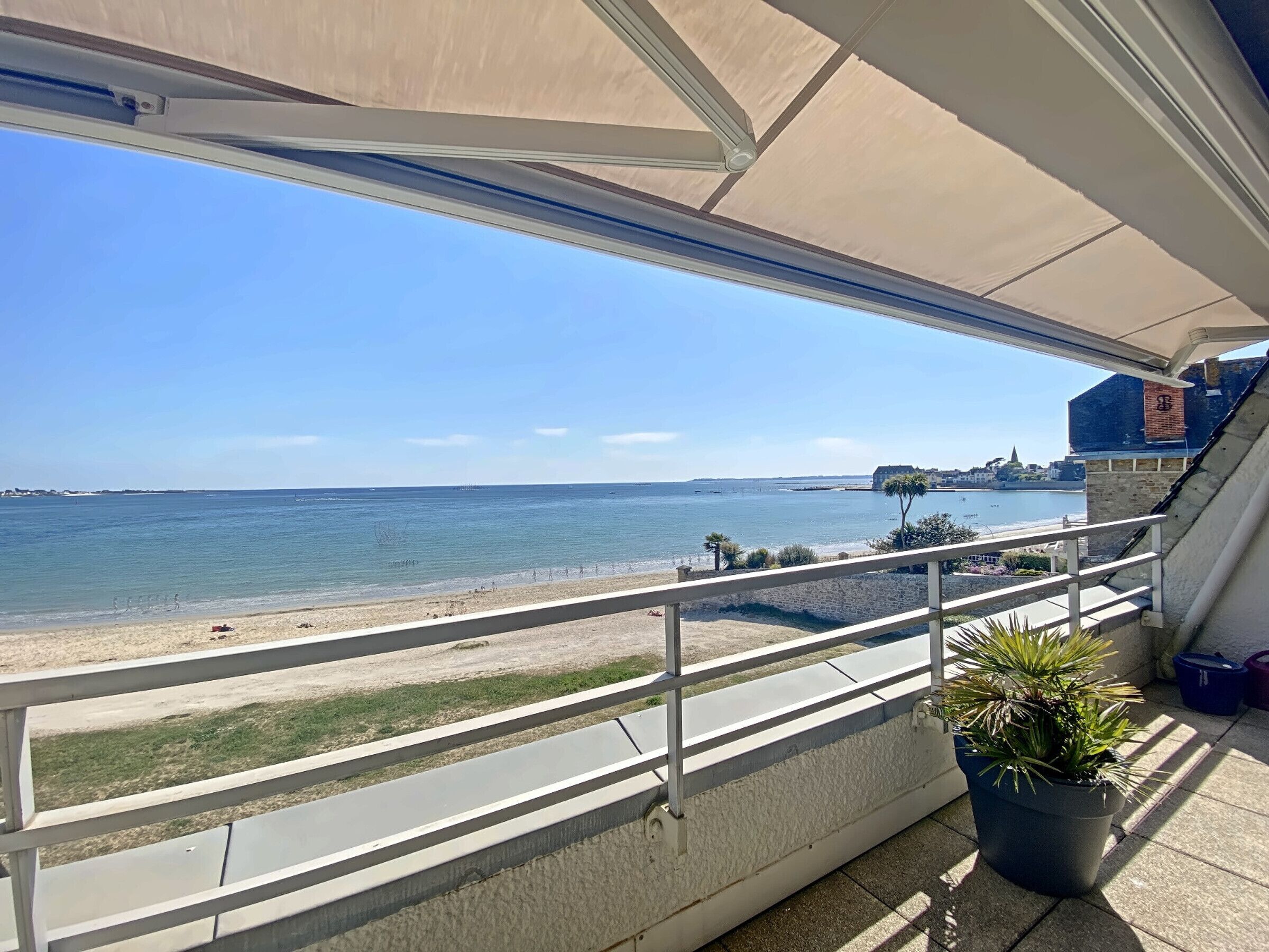 A balcony with a view of the sea and a distant cityscape.