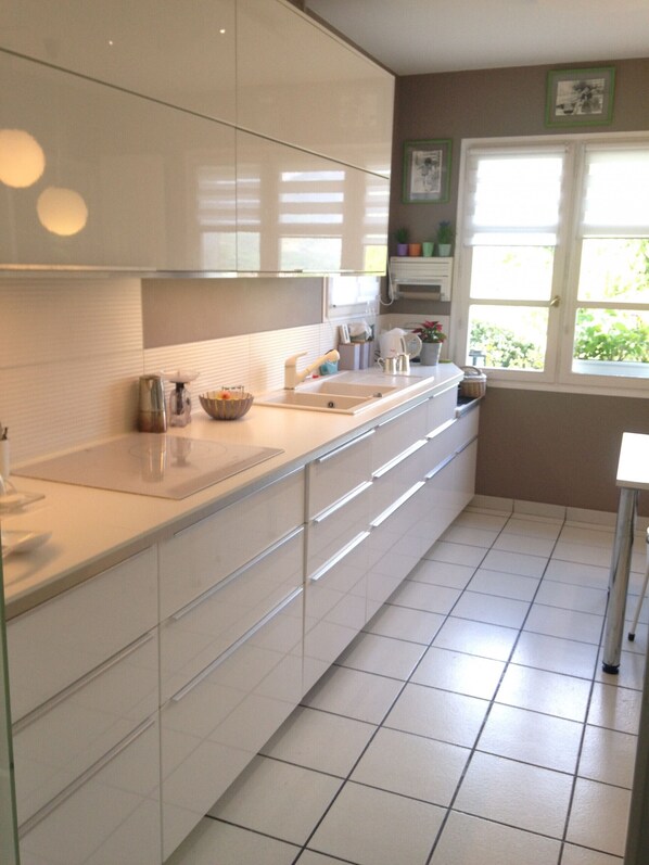 A modern kitchen with white cabinets, a double sink, and a window with a view of greenery. - ST-JORIOZ, Spacieuse villa, vue , 7/8 pers (Saint-Jorioz)